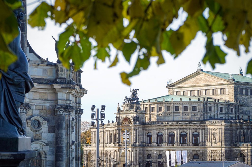 Blick auf die Dresdner Semperoper im Herbst, leicht verdeckt durch buntes Herbstlaub
