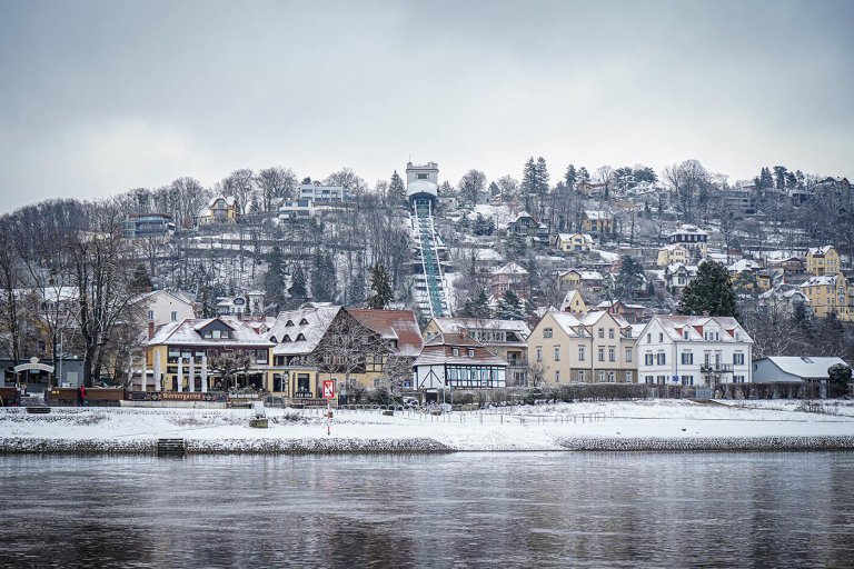 Blick auf das verschneite Elbufer und den Elbhang mit der Bergbahn in Dresden im Winter